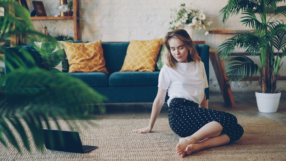 Young woman sitting on floor with laptop in living room.