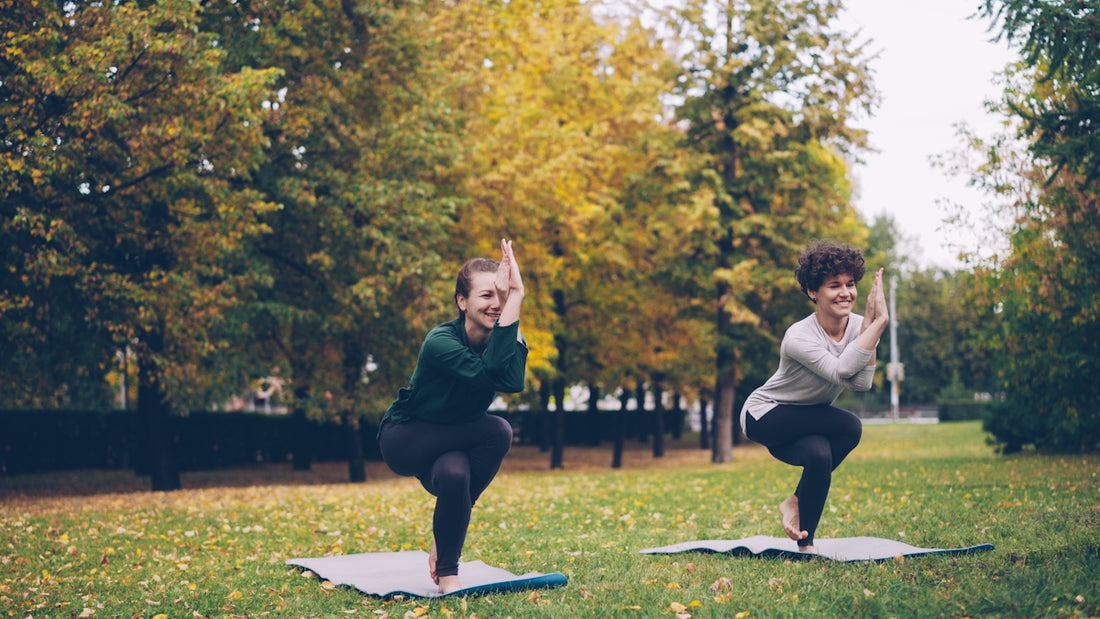 Two women practicing yoga in a park
